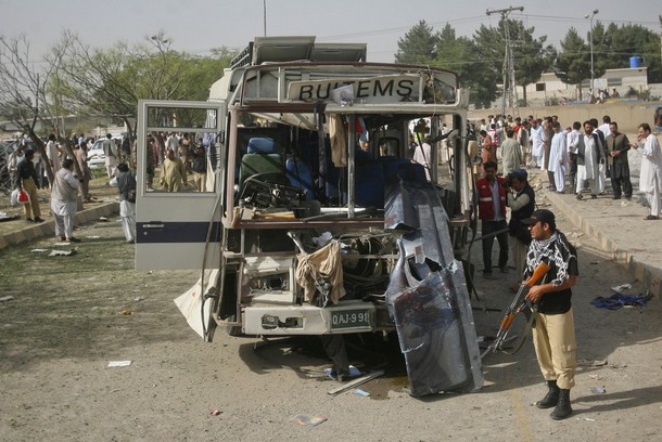 A policeman stands near a damaged bus which was hit by a bomb attack in Quetta